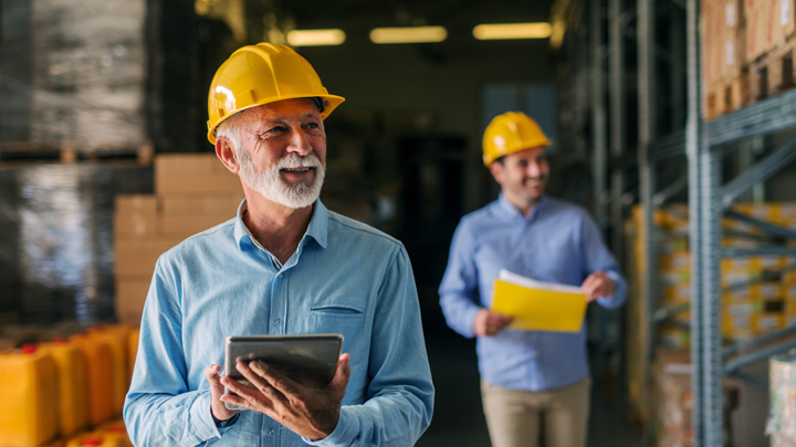 Business owner in yellow hard hat takes inventory in warehouse