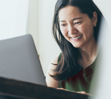 Woman smiles while working on a laptop computer