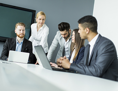 Business colleagues gathered around a table with laptops during a meeting.