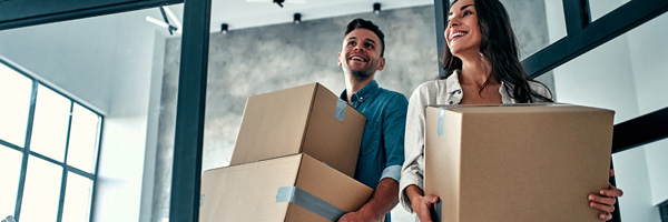 Young couple carries moving boxes into their urban apartment