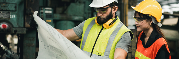 Construction professionals review a blueprint while working on-site