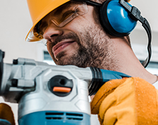 Contractor wears protective helmet, glasses and headphones while sanding