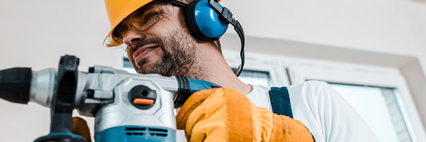 Contractor wears protective helmet, glasses and headphones while sanding