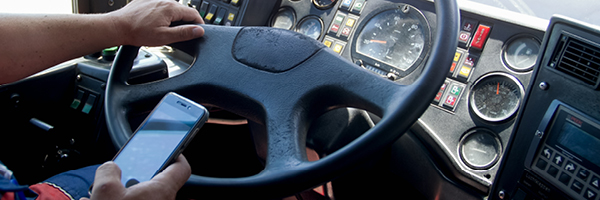 A semitruck driver steers vehicle while texting on a cell phone.