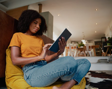 Smiling woman sits in a living room holding a tablet