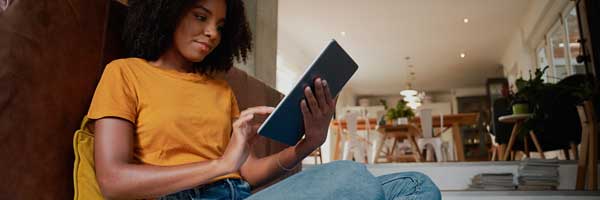 Smiling woman sits in a living room holding a tablet