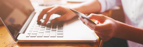 Person uses credit card and laptop to shop online