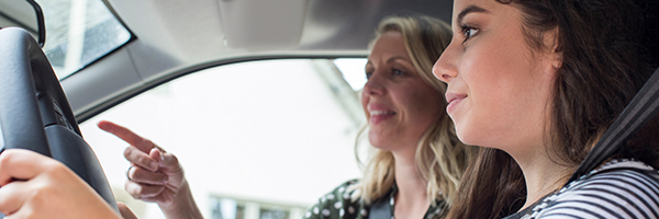 Parent teaching teenager how to drive a car