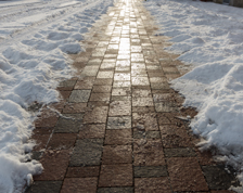 Shoveled snow clears a brick walking path.
