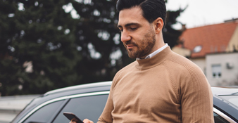 male sitting outside of car on phone