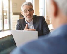 man on laptop conversing with another man