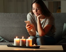 woman on phone sitting by candles