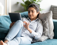 woman sitting on couch working on a tablet