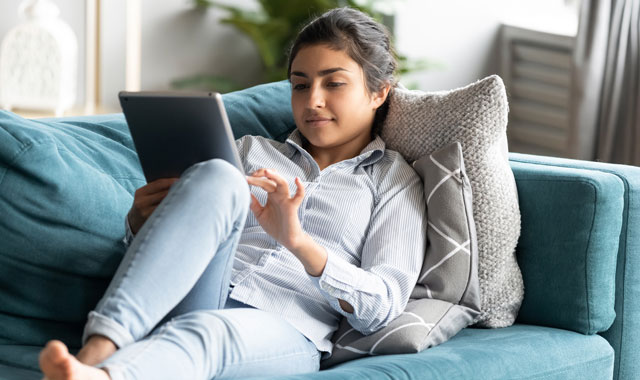 woman sitting on couch working on a tablet