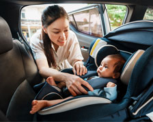 woman securing baby in car seat