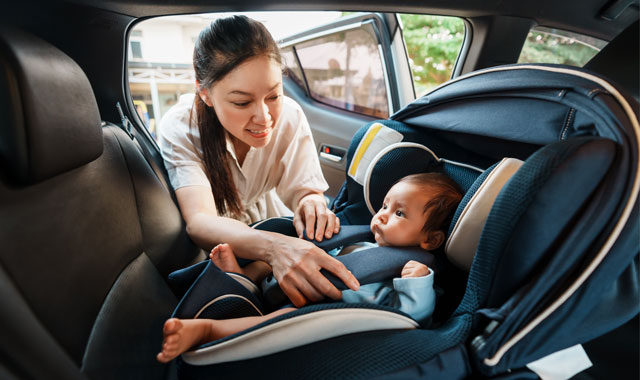 woman securing baby in car seat