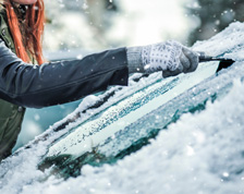 woman scraping ice of of car windshield