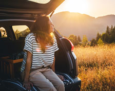 woman sitting in back of car staring out into field