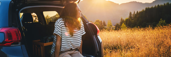 woman sitting in back of car staring out into field