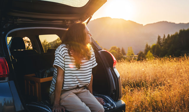 woman sitting in back of car staring out into field