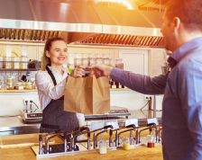 female grocery store worker handing bag to customer