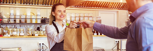 female grocery store worker handing bag to customer