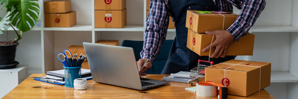 man carrying unopened boxes on laptop